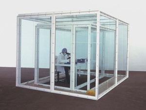 Damien Hirst, A Way of Seeing, 2000. Glass and steel vitrine, table, chair, ashtray, newspaper, slides, cup of tea, sponges, sand, glasses of water, and animatronic man with microscope, 96 × 156 × 120 inches (243.8 × 396.2 × 304.8 cm) © Damien Hirst and Science Ltd. All rights reserved, DACS 2018