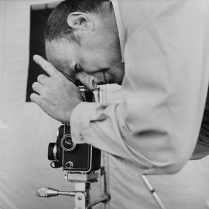 Black-and-white profile photograph of Irving Penn taking a photograph