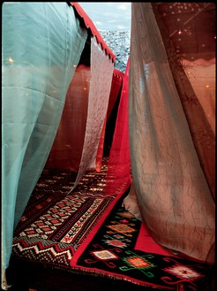 Chris Burden, Nomadic Folly, 2001 (detail) Wood platform, 4 cloth and metal umbrellas, woven carpets, braided ropes and pillows, silken fabrics, glass and metal lamps, and CD player and speakers, 11 ½ × 20 × 20 feet (3.5 × 6.1 × 6.1 m)© Chris Burden