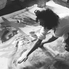 A photograph of Helen Frankenthaler working on a painting on the floor of her studio.