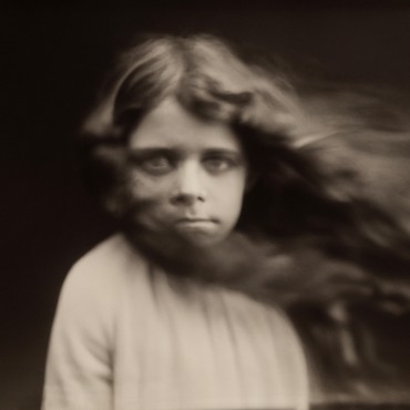 Sepia-toned image of a young girl with long hair blowing in the wind