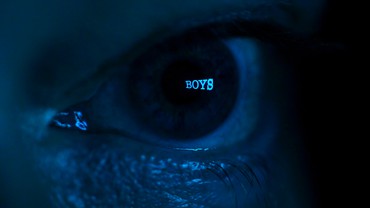 Close-up of an eye cast in blue light with the word "Boys" over the pupil
