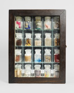 Joseph Cornell Pharmacy, 1943. Glass-paned wood cabinet, marbled paper, mirror, glass shelves, and twenty glass bottles containing various paper cuttings (crêpe, tissue, printed engravings, and maps), colored sand, pigment, colored aluminum foil, feathers, paper butterfly wing, dried leaf, glass marble, fibers, driftwood, wood marbles, glass rods, beads, seashells, crystals, stone, wood shavings, sawdust, sulfate, copper, wire, fruit pits, paint, water, and cork, 15 ¼ × 12 × 3 ⅛ inches (38.7 × 30.5 × 7.9 cm) © 2025 The Joseph and Robert Cornell Memorial Foundation/Licensed by VAGA at Artists Rights Society (ARS), New York. Photo: Dominique Uldry