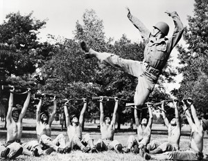 Black and white image of a group of people dancing, they are all dressed in military uniforms