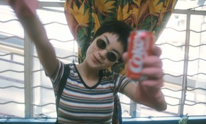 Film still featuring actress Faye Wong looking and smiling at the camera while holding a can of Coke
