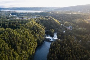 An eagle's eye of view of Kistefos's the Twist building: a twisted silver bridge-like building over a river surrounded by greenery