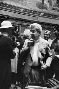 Black and white portrait of Jacques Lacan wearing a pinstripe suit and smoking a cigarette