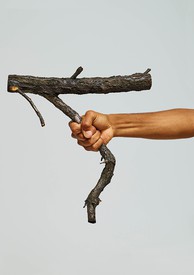 A hand holds a tree branch like a gun