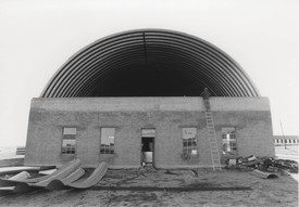 Black and white image of Donald Judd inspecting the new roof on the south Artillery Shed, Marfa, Texas, c. 1984.