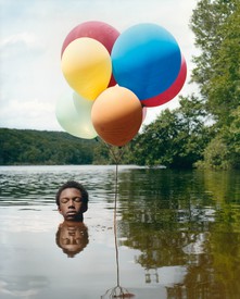 Image of boy submerged in water with multi-colored balloons