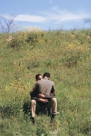 Two people embracing and sitting on a large grass field