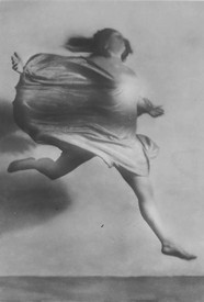 Blurred black-and-white photograph of Mary Wigman performing Hexentanz (Witch Dance) in 1926 in Berlin. Wigman leaps in profile with her dress and hair flowing behind her.