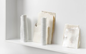 Five white objects lined up on a white shelf