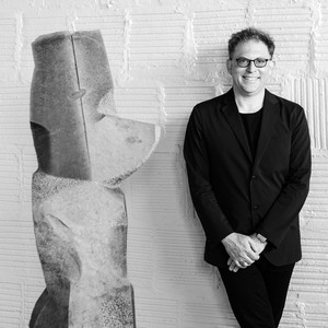 Black-and-white portrait of Brett Littman standing next to a sculpture