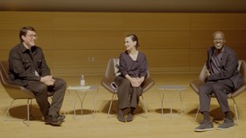 Three people, in mid-conversation, sit on chairs next to each other