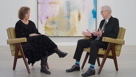 Carol Armstrong and John Elderfield seated in front of a painting by Helen Frankenthaler