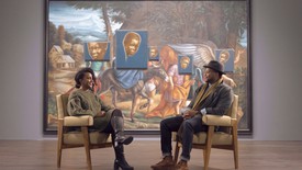 Titus Kaphar and Zoé Whitley sit in front of the artist’s artwork