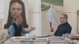 Y.Z. Kami and Steven Henry Madoff sit in front two of the artist's paintings