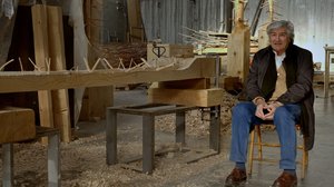 Giuseppe Penone sitting in a chair in his studio next to a wood sculpture in progress