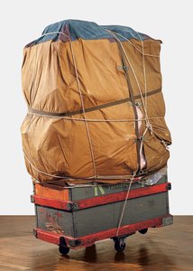 Luggage wrapped in canvas with ropes and straps placed on top of a blue and red dolly